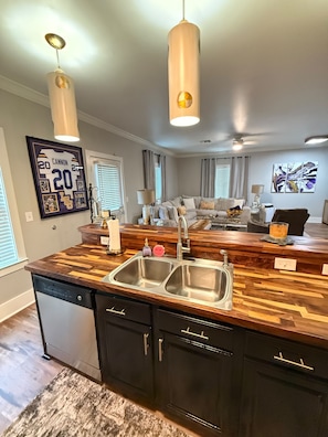 A modern kitchen with a wooden countertop, double sink, and built-in cabinets.