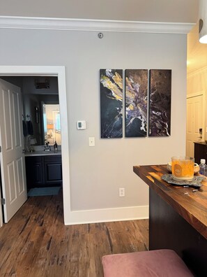 A modern kitchen with dark wood flooring, a marble backsplash, and a bar area with a candle.