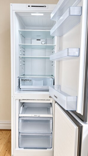 An interior of a white refrigerator with multiple shelves and drawers, including a 'MultiBox' compartment for vegetables and fruit. - Spacious 3BR Walk to Camden, Euston & King’s Cross (Greater London)
