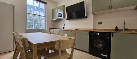 A modern kitchen with a dining area, built-in appliances, and a large window.