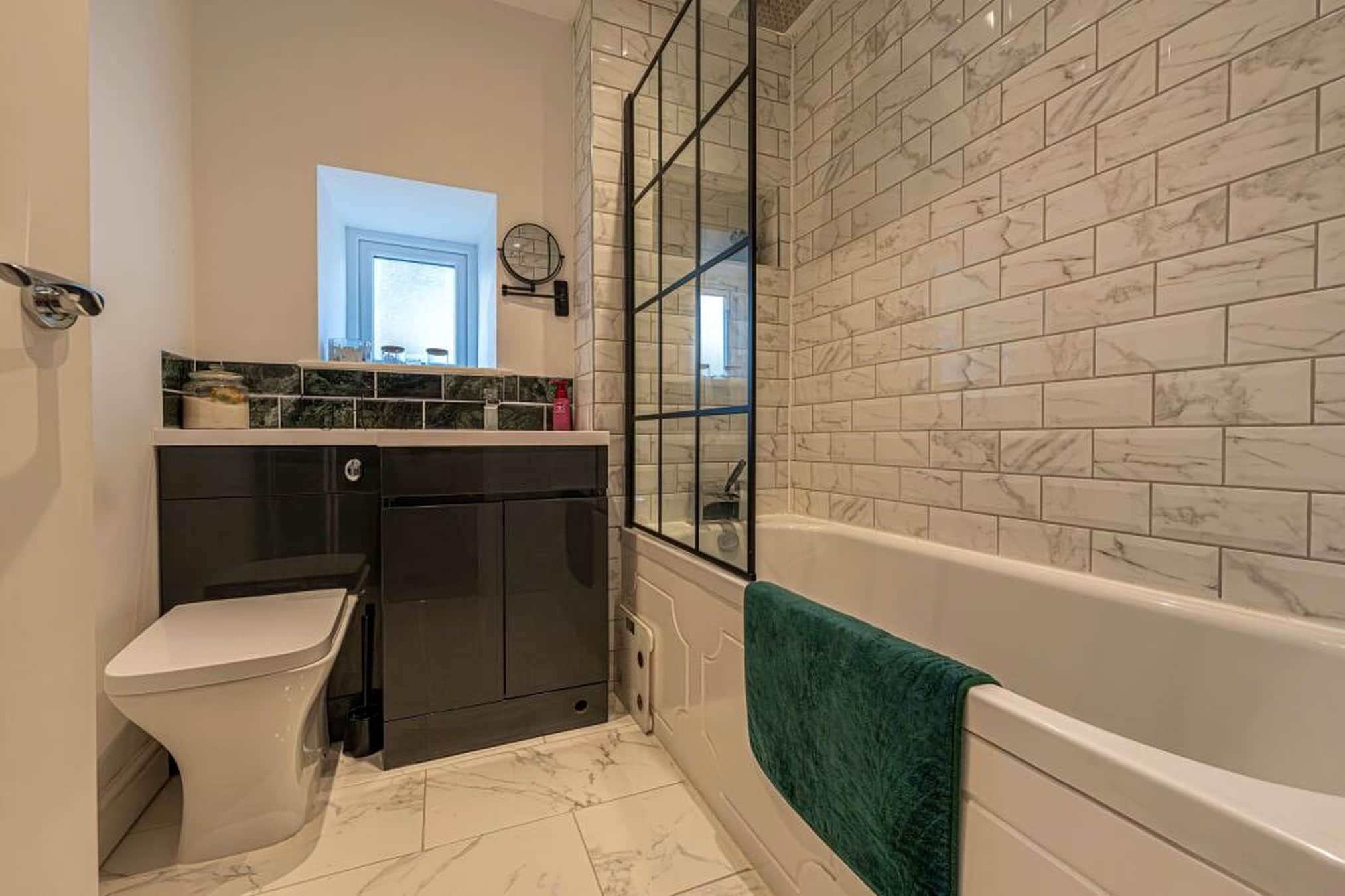 A bathroom with a toilet, a sink, a mirror, and a bathtub.