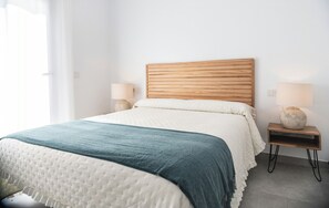 A neatly made bed with a wooden headboard, two bedside lamps, and a decorative vase on a nightstand. - House with fireplace and private pool in Andalusia (Luque)