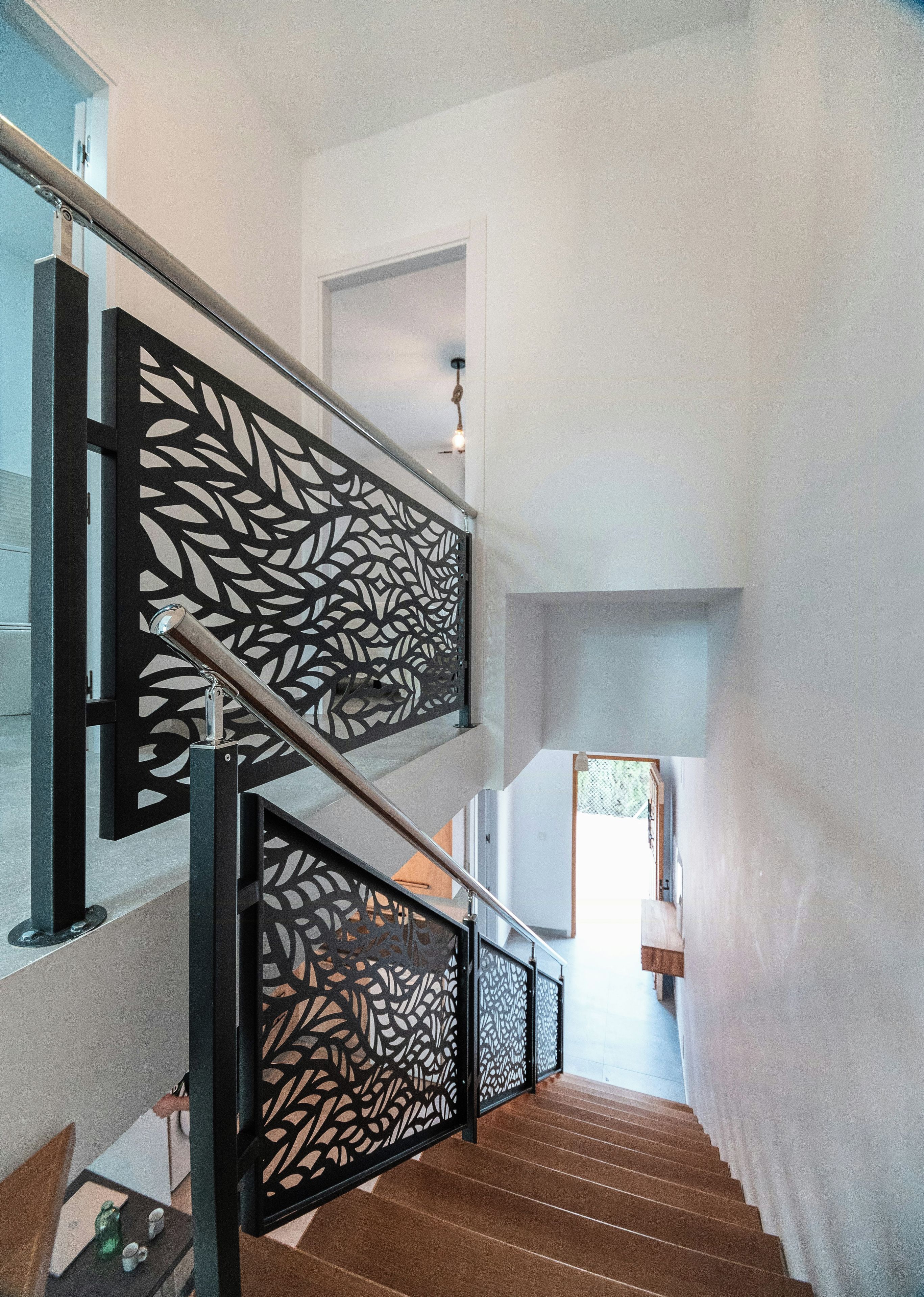 Una escalera de diseño moderno con barandilla negra y motivo de hojas.