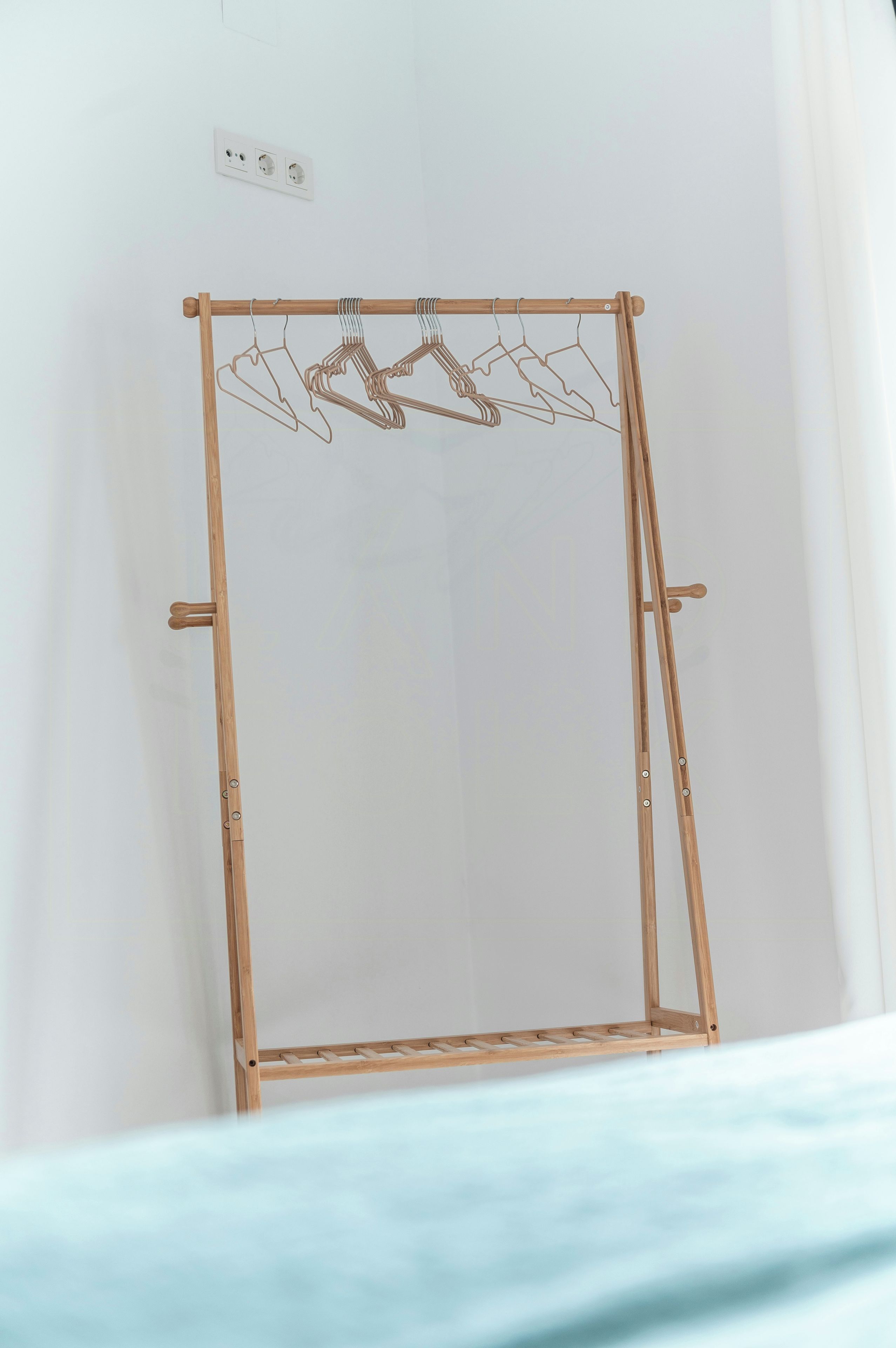 Ein Wäscheständer aus Holz mit Kleiderbügeln vor einer schlichten Wand.