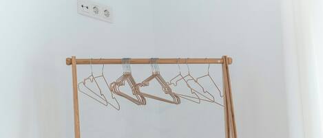 Ein Wäscheständer aus Holz mit Kleiderbügeln vor einer schlichten Wand.