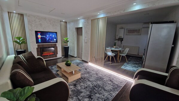 Una sala de estar moderna con televisor de pantalla plana, chimenea y comedor con mesa y sillas.