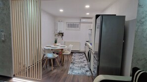 A compact kitchen with a refrigerator, a dining table with chairs, and a radiator.