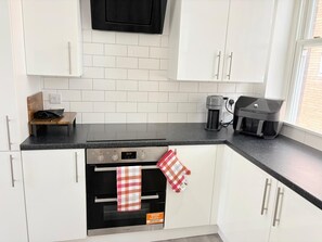A kitchen with white cabinets, a black countertop, a coffee maker, and a toaster. - well furnished flat at city center (Kingston upon Hull)
