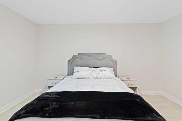 Ein Schlafzimmer mit einem Bett, zwei Nachttischen und einer schwarzen Tagesdecke.