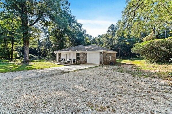 A single-story house with a covered porch, a garage, and a gravel driveway.