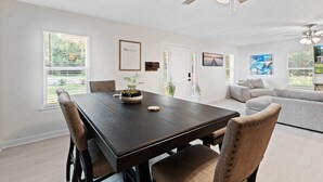 Un espace repas moderne avec une table en bois foncé, des chaises rembourrées et un ventilateur de plafond.