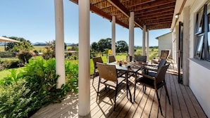 Eine Terrasse im Freien mit Holzboden, weißen Säulen und einem Esstisch.