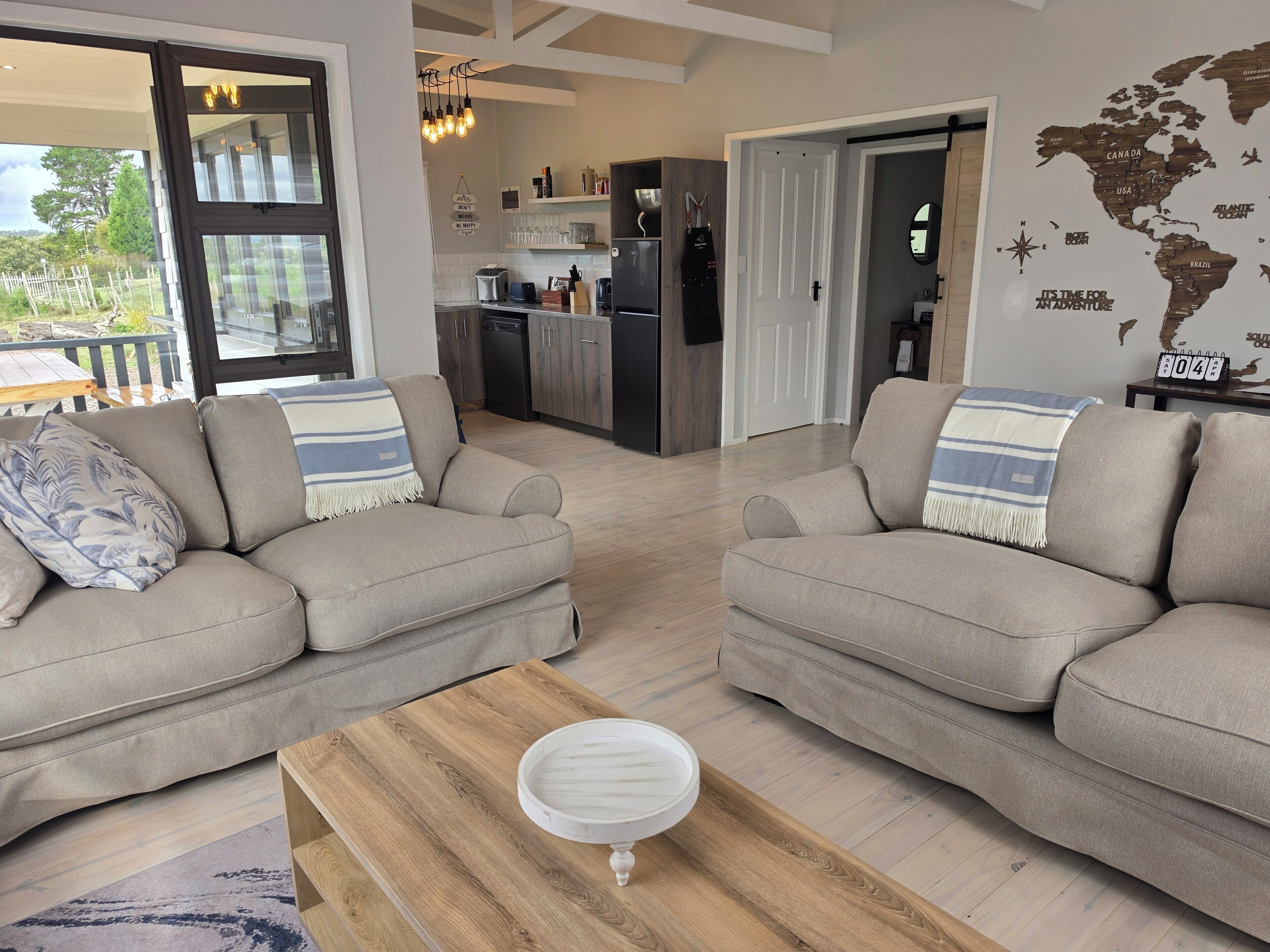 Ein modernes Wohnzimmer mit zwei Sofas, einem Couchtisch und einer Küche im Hintergrund.