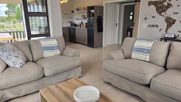 Ein modernes Wohnzimmer mit zwei Sofas, einem Couchtisch und einer Küche im Hintergrund.