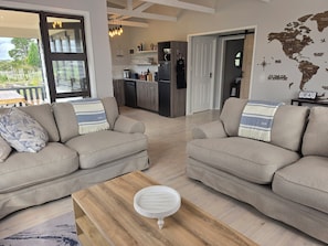 A modern living room with two sofas, a coffee table, and a kitchen in the background.