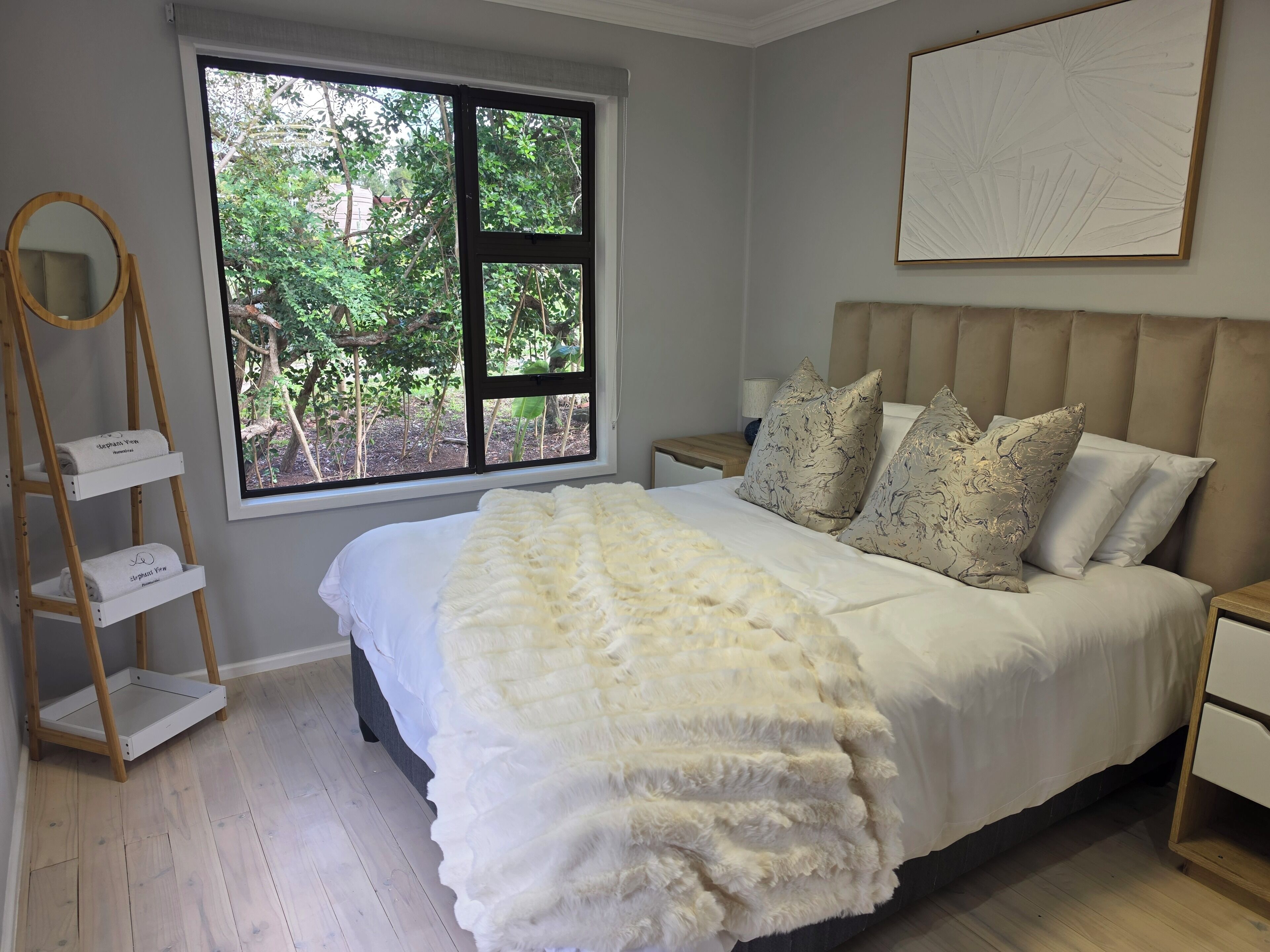 Ein Schlafzimmer mit einem großen Fenster, einem Bett mit weißer Bettwäsche und einer Holzleiter.