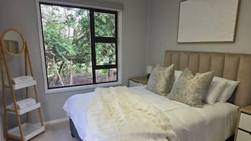 Ein Schlafzimmer mit einem großen Fenster, einem Bett mit weißer Bettwäsche und einer Holzleiter.