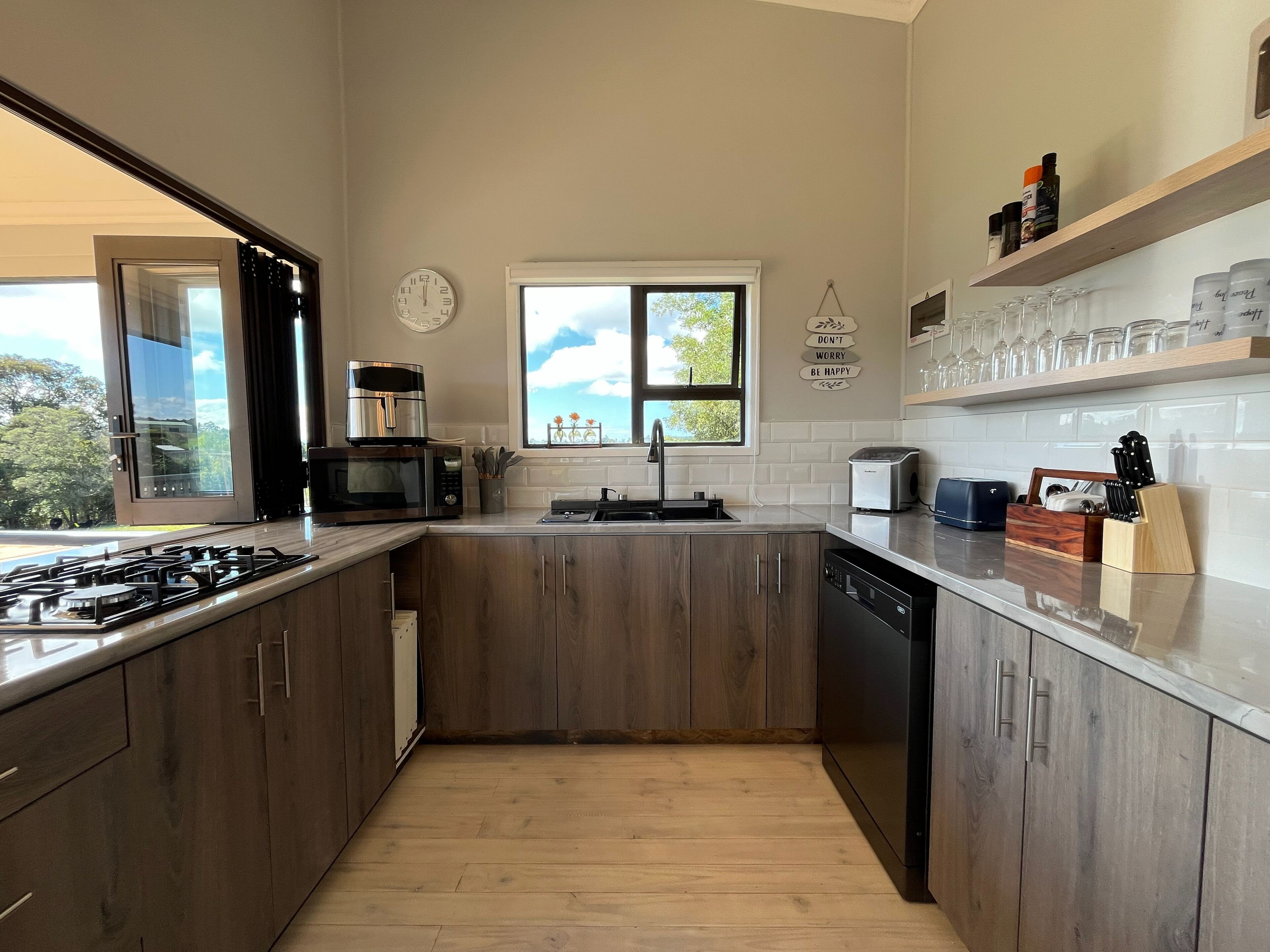 Una cocina moderna con armarios de madera, estufa a gas, microondas, tostadora y lavavajillas.