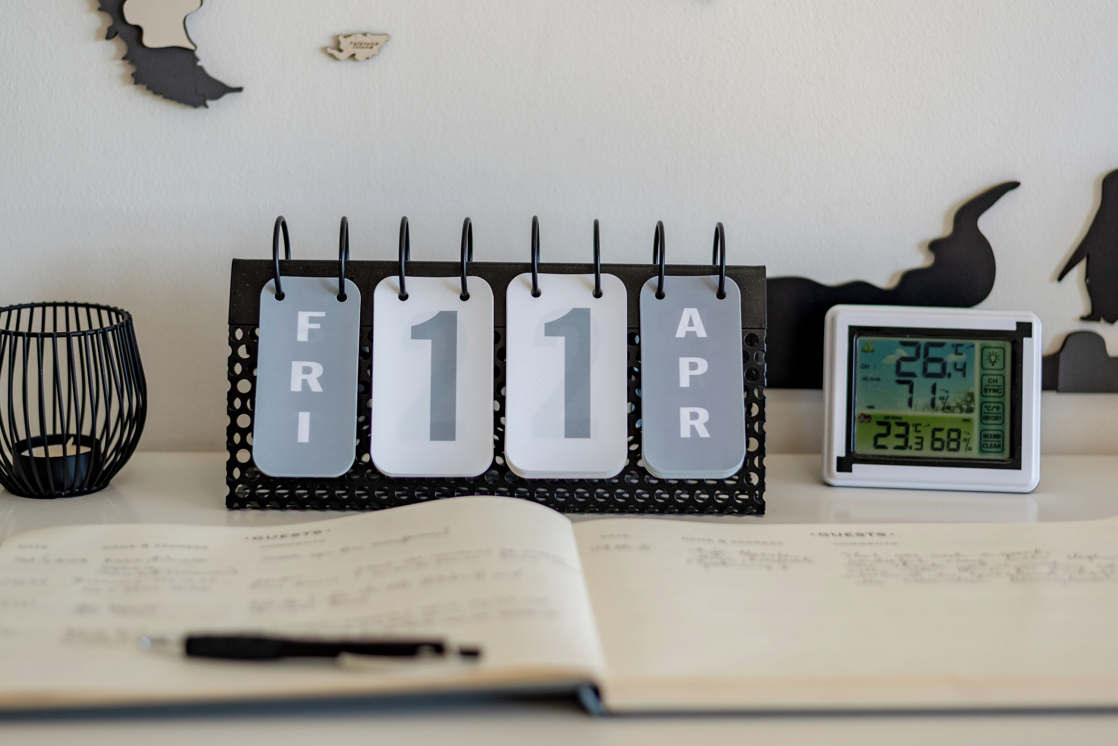 Un escriptori amb un calendari que mostra l'11 d'abril, un rellotge digital i una ploma sobre un quadern obert.
