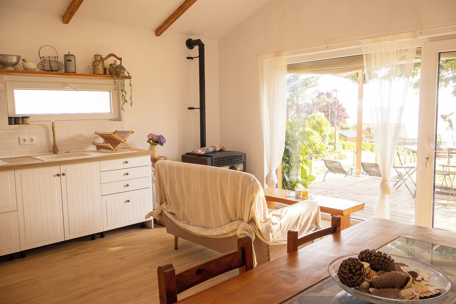 A cozy kitchen with a dining area, a wooden table, and a view through a glass door.