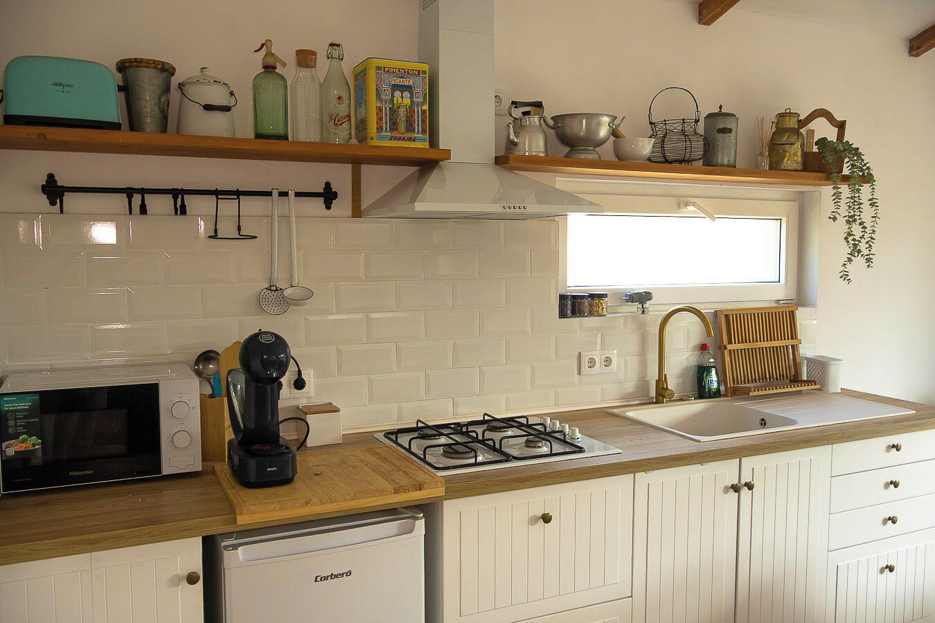 A kitchen with white cabinetry, a gas stove, a microwave, and various kitchen utensils on shelves.