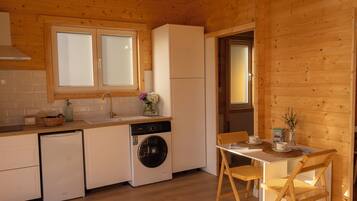 A compact kitchen with a washing machine, a sink, and a dining area with a table and chairs.