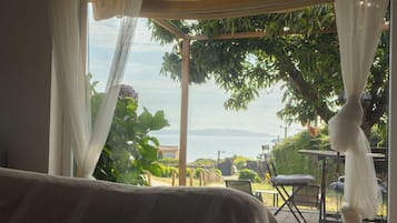 Habitación con vista al mar, una pérgola de madera y mobiliario exterior.
