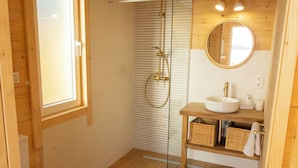 A wooden interior with a glass shower enclosure, a wooden vanity with a sink, and a mirror. - Raíces da costa Ártabra (A Coruña)