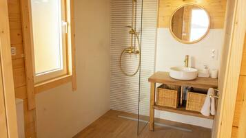 A wooden interior with a glass shower enclosure, a wooden vanity with a sink, and a mirror.