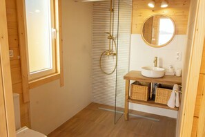 Un interno in legno con cabina doccia in vetro, mobile bagno in legno con lavandino e specchio.
