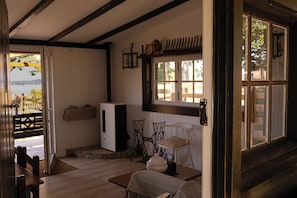 Una habitació acollidora amb sostre de fusta, nevera blanca, taula de dinar amb caires i finestra amb vista a l'exterior.