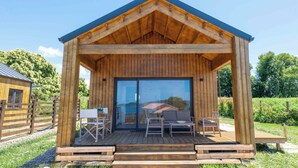 A wooden cabin with a covered porch, a sliding glass door, and outdoor seating.