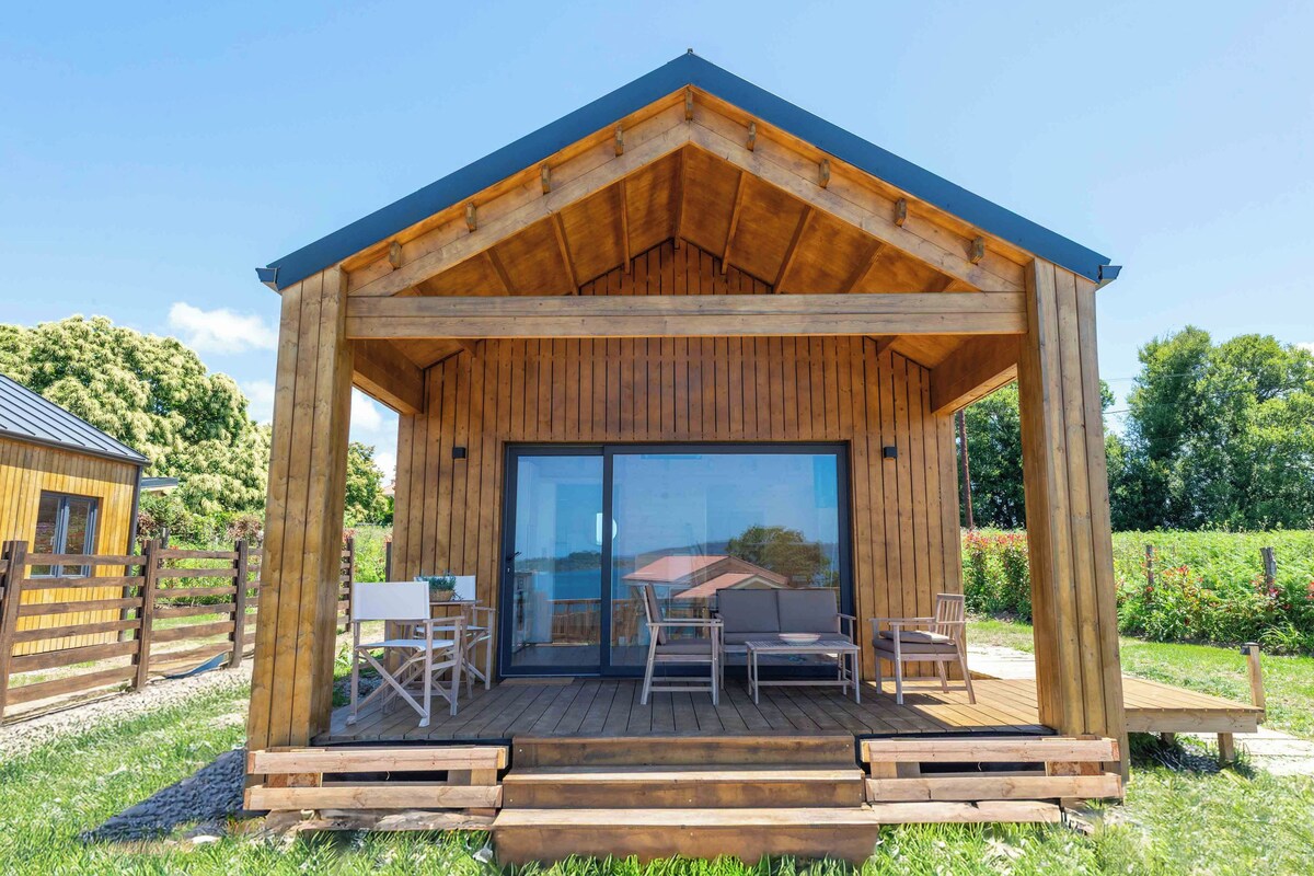 A wooden cabin with a covered porch, a sliding glass door, and outdoor seating.