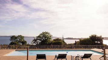 Una piscina con sillones de descanso y vistas al mar.