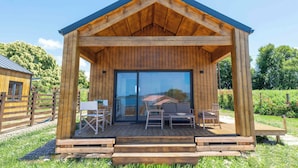 A wooden cabin with a covered porch, a sliding glass door, and outdoor seating. - Raíces da costa Ártabra (A Coruña)