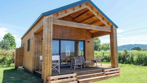 A wooden cabin with a covered porch, large windows, and a view of the surrounding landscape. - Raíces da costa Ártabra (A Coruña)
