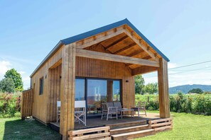 Una baita di legno con veranda coperta, ampie finestre e vista sul paesaggio circostante.
