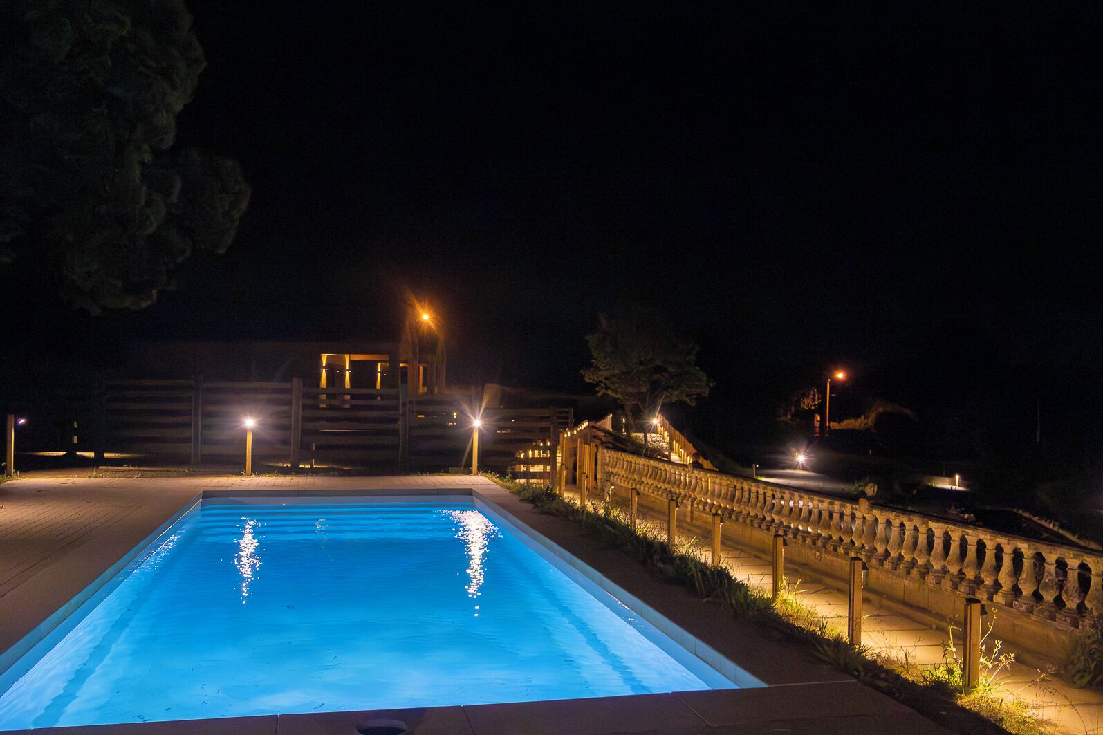 Una piscina por la noche con edificios circundantes y farolas.