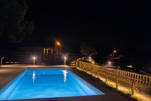 Una piscina por la noche con edificios circundantes y farolas.