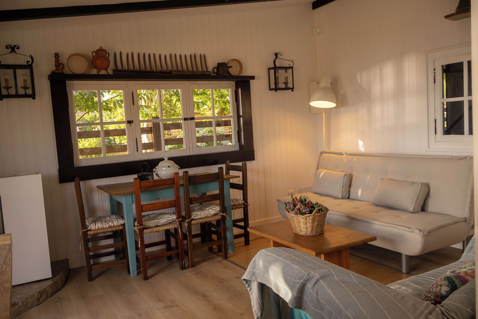 Una habitación acogedora con una mesa de madera, sillas, un sofá y una ventana con vistas a zonas verdes.
