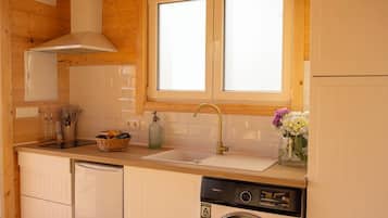 Cocina compacta con armarios de madera, lavavajillas integrado, ventana sobre el fregadero y una cesta de fruta en la encimera.