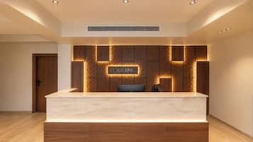 A reception desk with a sign that reads 'TOURING' and a modern, geometric wall design behind it.