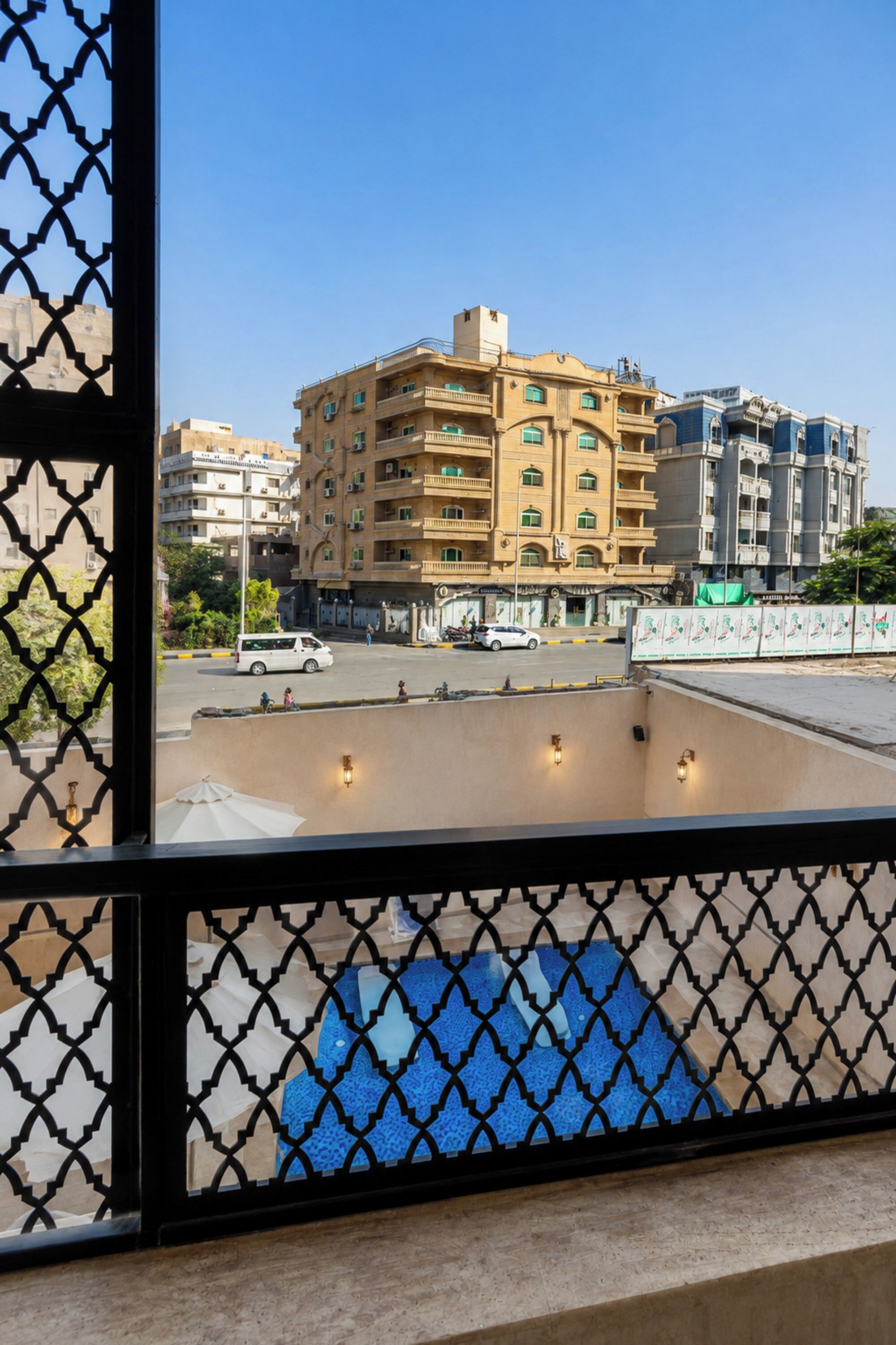 A view of a building with multiple floors and balconies, a parking area, and a clear sky.