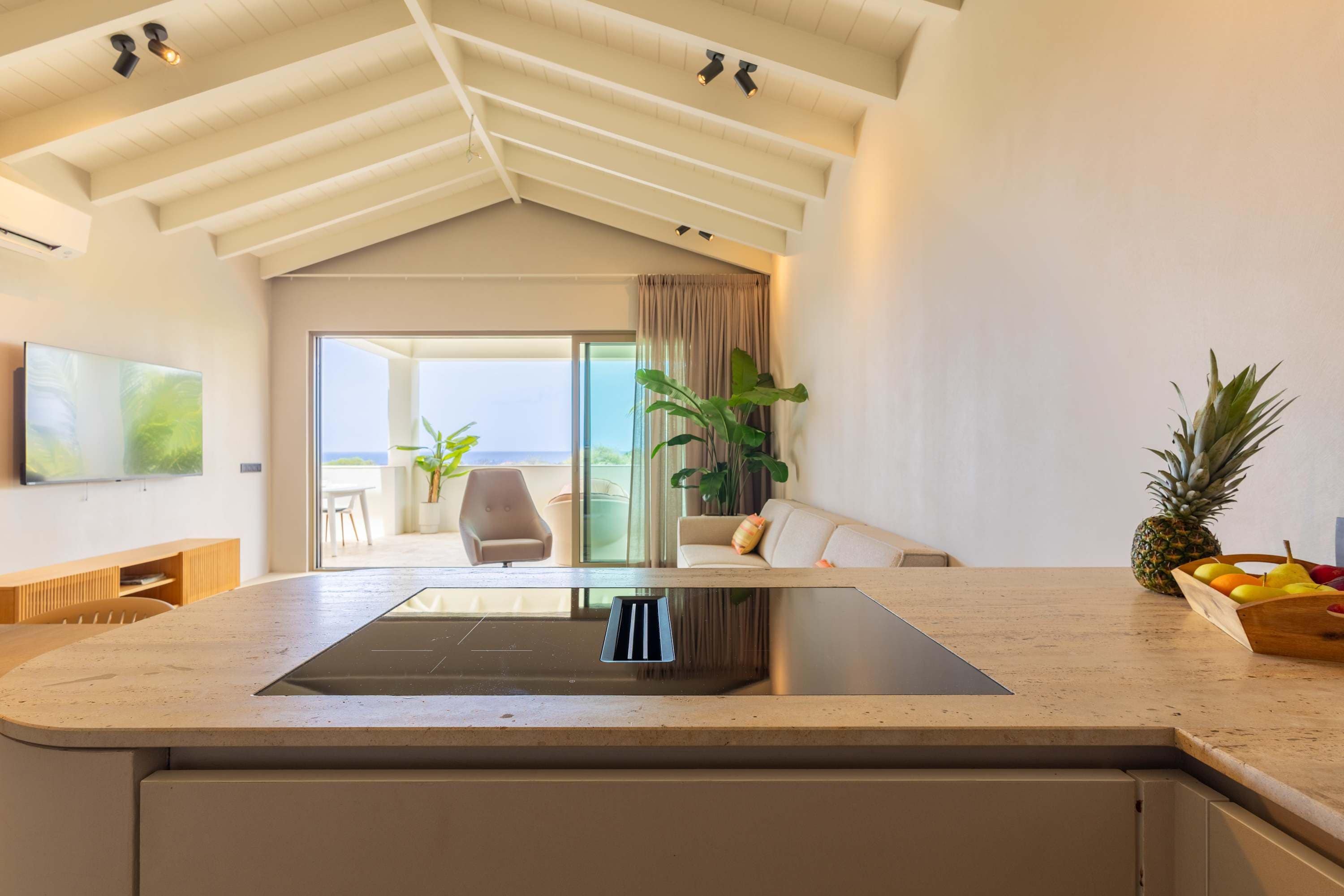 A modern kitchen with a central island, a dining area with a sofa and chairs, and a view of the outdoors.