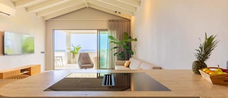 A modern kitchen with a central island, a dining area with a sofa and chairs, and a view of the outdoors.