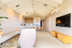 A modern living space with a sofa, a dining area, and a TV mounted on the wall. - Azzurro at The Reef Ocean View Penthouse (Sint Michiel)