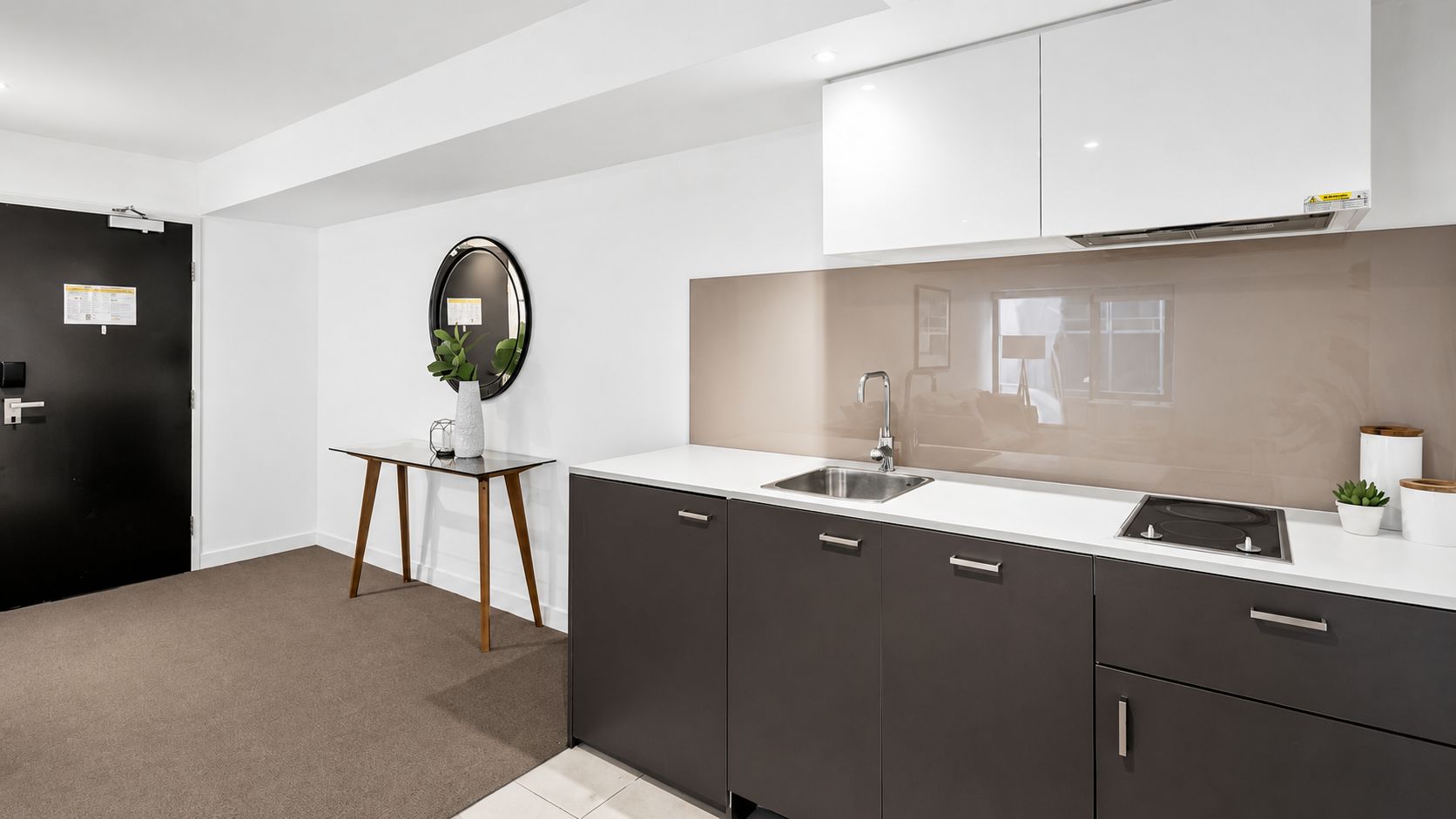 A modern kitchen with a built-in sink, dark cabinets, and a white countertop.