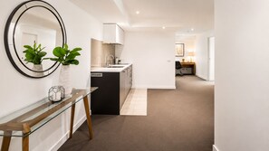 A modern kitchen with a black island, white cabinets, and a glass table with plants. - Spacious 70m² St Kilda Rd Stay Near Alfred Hospital with Gym,Parking & Workspace (Melbourne)