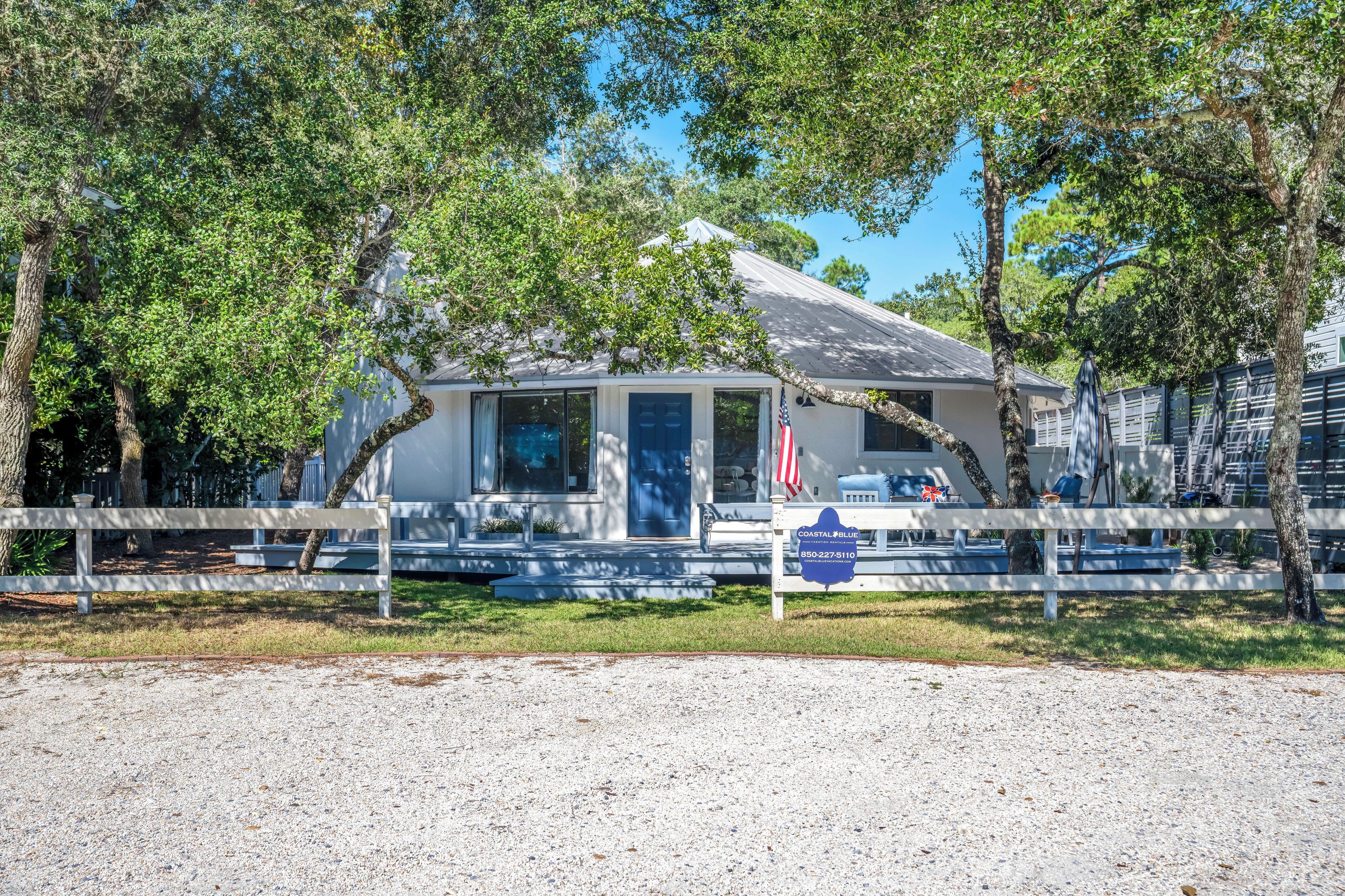 A coastal-style building with a flag, a signboard, and a gravel driveway.