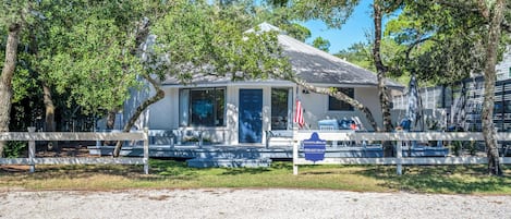 A coastal-style building with a flag, a signboard, and a gravel driveway.